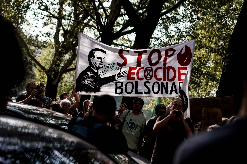 Protesters hold a banner  as they gather in front of the Brazilian Embassy for a demonstration organized by Extinction Rebellion activists in Brussels, Belgium, on Monday, calling on Brazil to act to protect the Amazon rainforest from deforestation and fire. — AFP