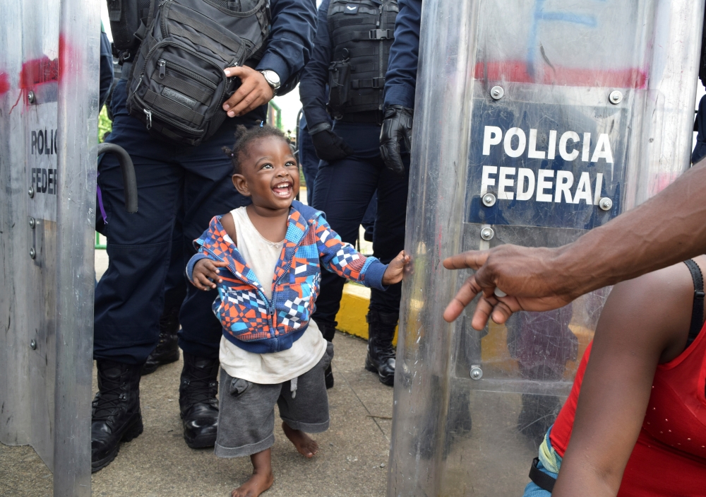 A girl plays next to a barricade by riot police while migrants from Haiti and Africa protest outside the Siglo XXI immigrant detention center, demanding that Mexican migration authorities to speed up their humanitarian visas to cross the country towards the U.S., in Tapachula, Mexico, on Monday. — Reuters