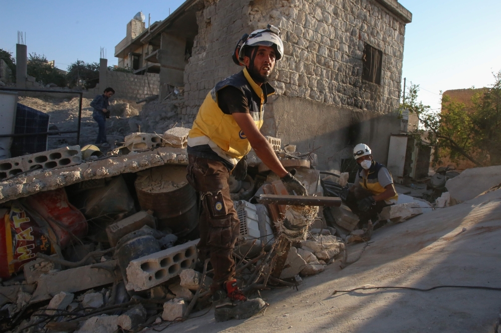 Members of the Syrian Civil Defense (White Helmets) look for survivors under the rubble of a building following a reported airstrike by Syrian regime forces in Maar Shurin on the outskirts of Maaret Al-Numan in northwest Syria on Tuesday. — AFP