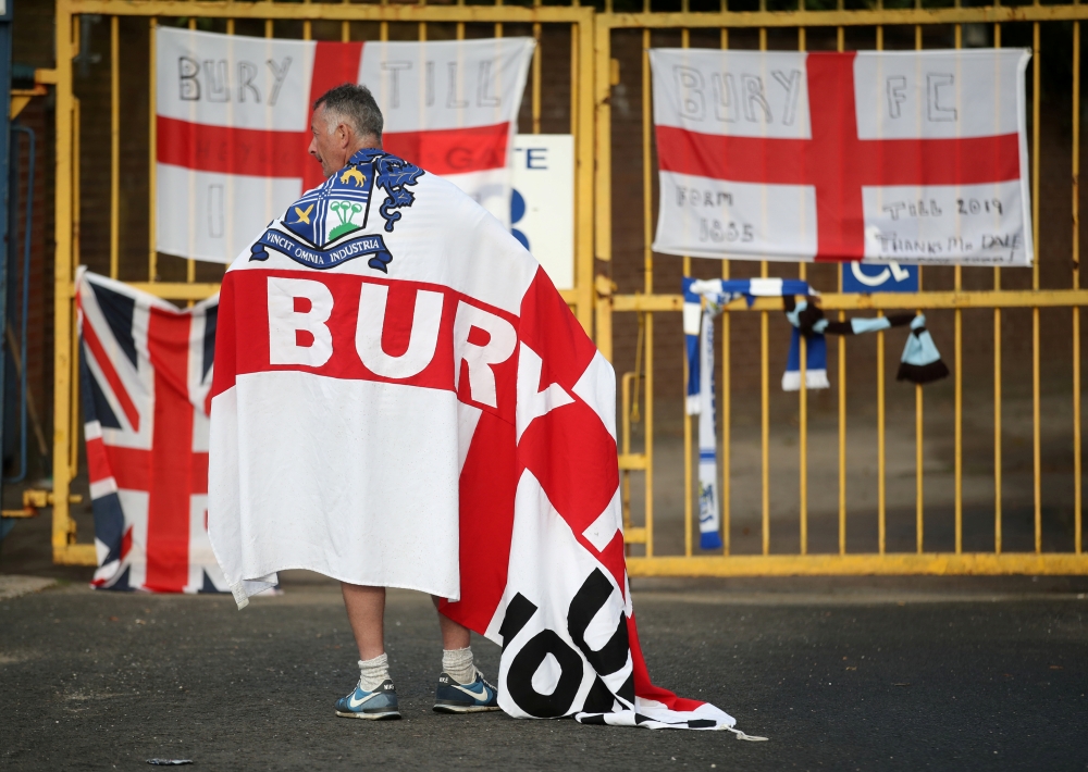 A Bury FC fan wears a flag outside the stadium Gigg Lane, Bury, Britain, on Tuesday. — Reuters