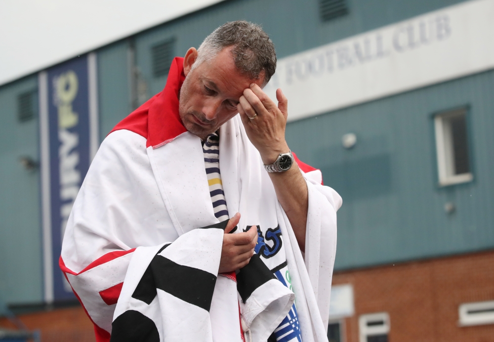 A Bury FC fan wears a flag outside the stadium Gigg Lane, Bury, Britain, on Tuesday. — Reuters