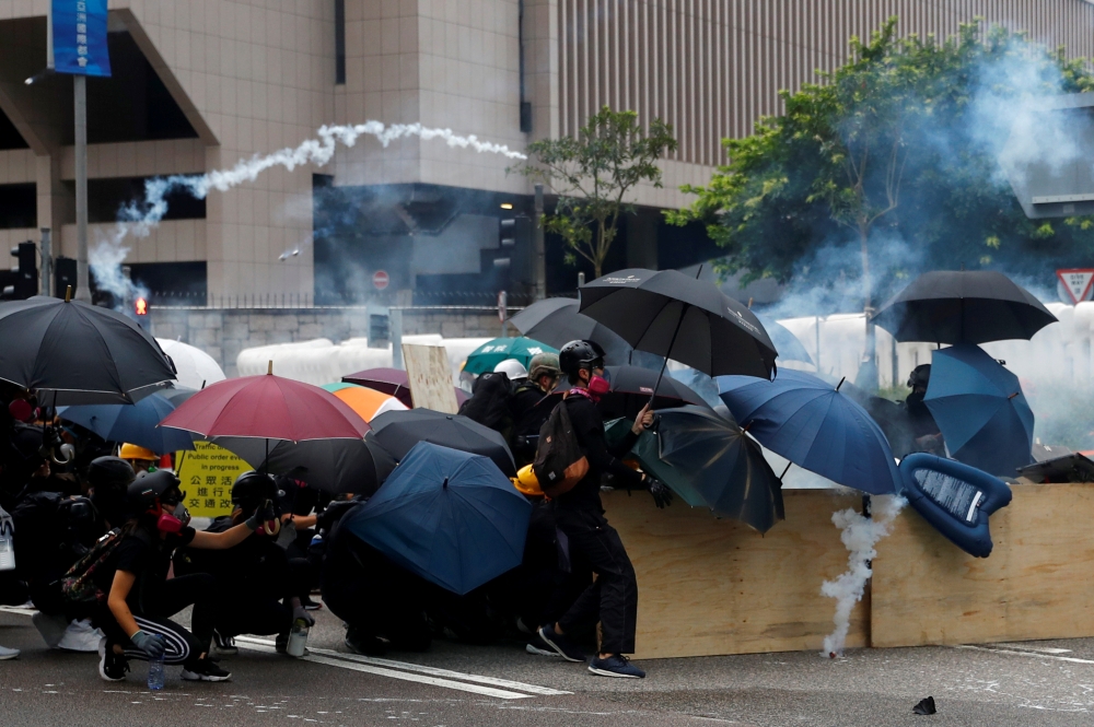 Demonstrators take cover as police fire tear gas during a protest in Hong Kong, on Saturday. -Reuters