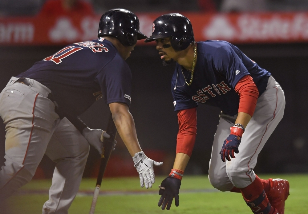 Rafael Devers No. 11 of the Boston Red Sox congratulates Mookie Betts No. 50 for his solo home run in the 15th inning against the Los Angeles Angels at Angel Stadium of Anaheim on Friday in Anaheim, California. The Red Sox won 7-6 in 15 innings. — AFP