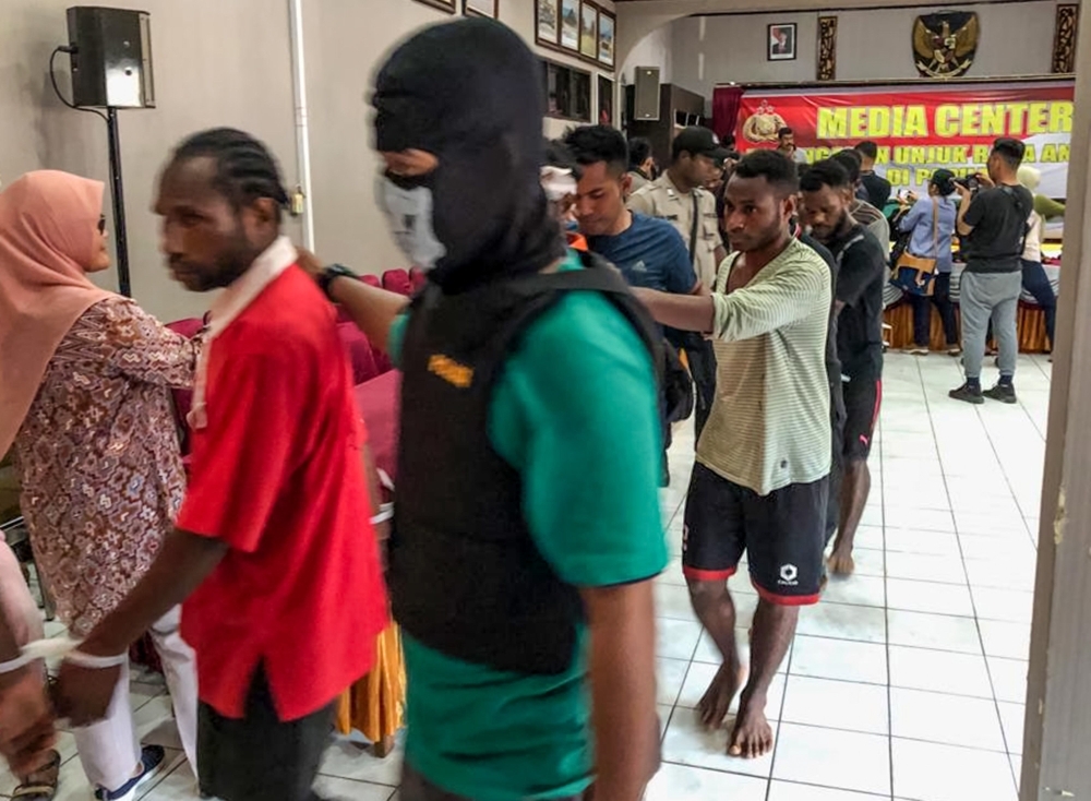 Indonesian plainclothes police escort suspects of a riot in Jayapura, Papua province on Saturday. -Courtesy photo 