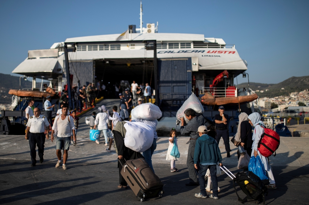 Migrants from Afghanistan board a catamaran that will transfer them to the mainland, in Mytilene on the island of Lesbos, Greece, on Monday. -Reuters