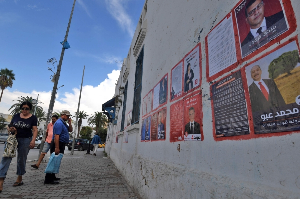 A man looks at posters of Tunisian presidential candidates in the capital Tunis on Monday. — AFP