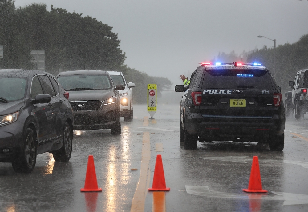 A Highland Beach police officer sits in his vehicle to check id's of people in cars as he only allows residents to enter the Highland Beach area as Hurricane Dorian continues to make its way toward the Florida coast in Highland Beach, Florida, on Monday. — AFP