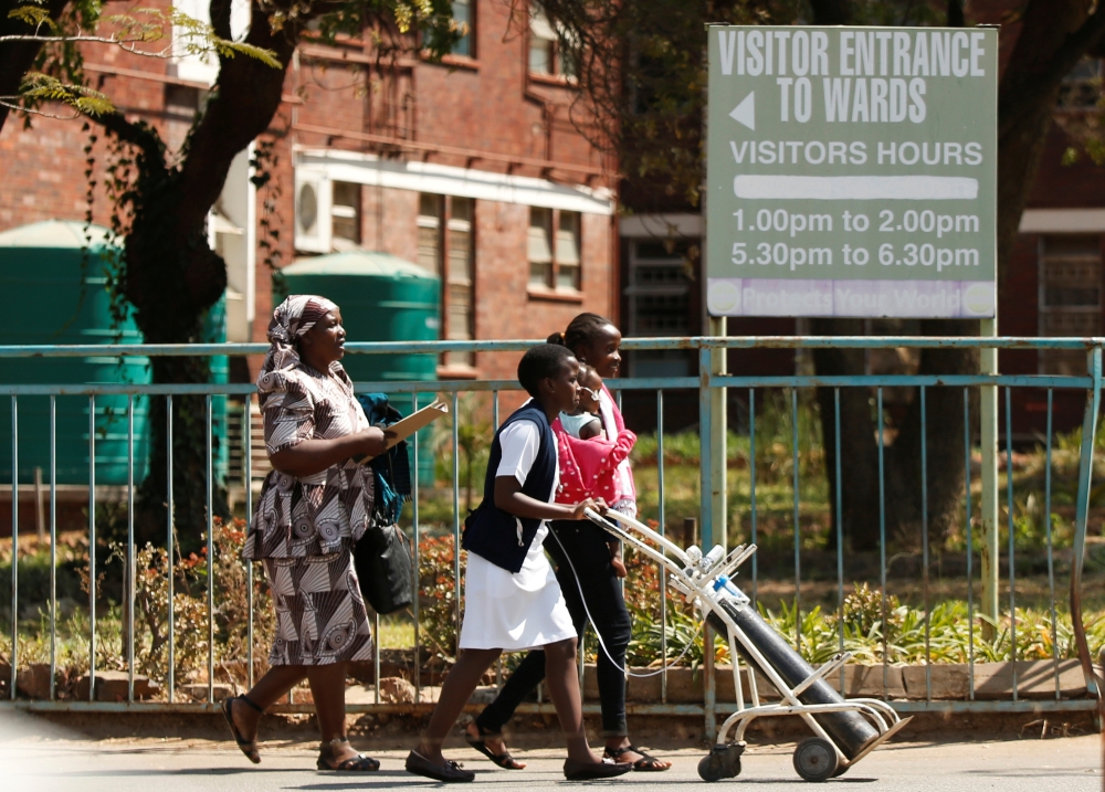 A nurse assisits a mother and her child outside Harare Central Hospital as the country's public sector doctors began a strike in Harare, Zimbabwe, on Tuesday. — Reuters