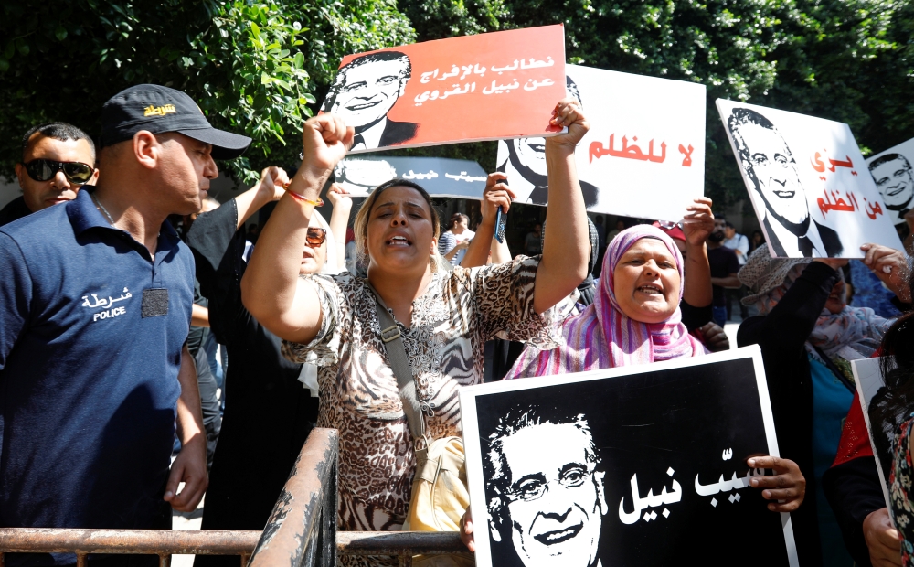 Supporters of presidential candidate Nabil Karoui, hold his picture as they take part in a rally in front of the courthouse asking for his release from prison in Tunis, Tunisia, on Tuesday. — Reuters