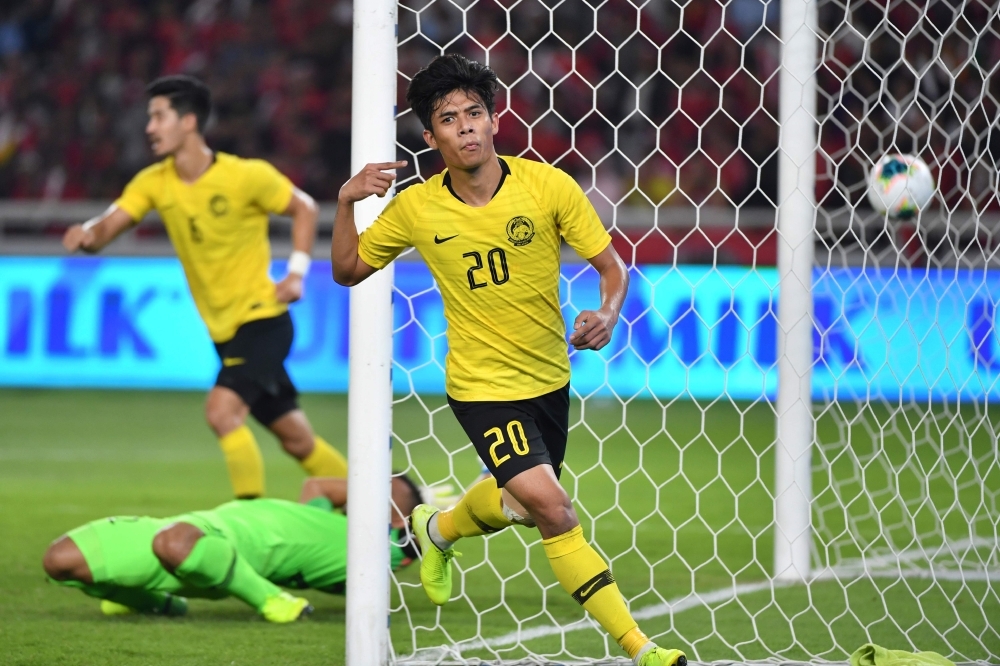 Malaysia's Muhammad Syafiq Ahmad (R) celebrates after scoring a goal during FIFA world cup preliminary qualification round 2 at the Gelora Bung Karno stadium di Jakarta on Thursday. — AFP 