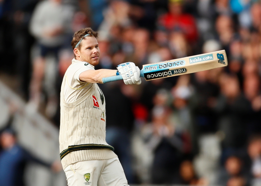 England's Jos Buttler (C) jumps over the ball as Australia's Steve Smith (R), who cracked a double century, hits a shot on the second day of the fourth Ashes cricket Test match at Old Trafford in Manchester, northwest England on Thursday.  — AFP