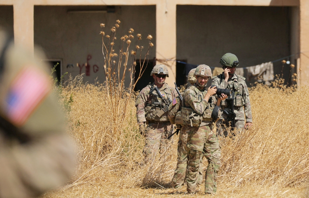 Turkish and American soldiers stand near a former YPG military point during a joint US-Turkey patrol, near Tel Abyad, Syria on Sunday. — Reuters