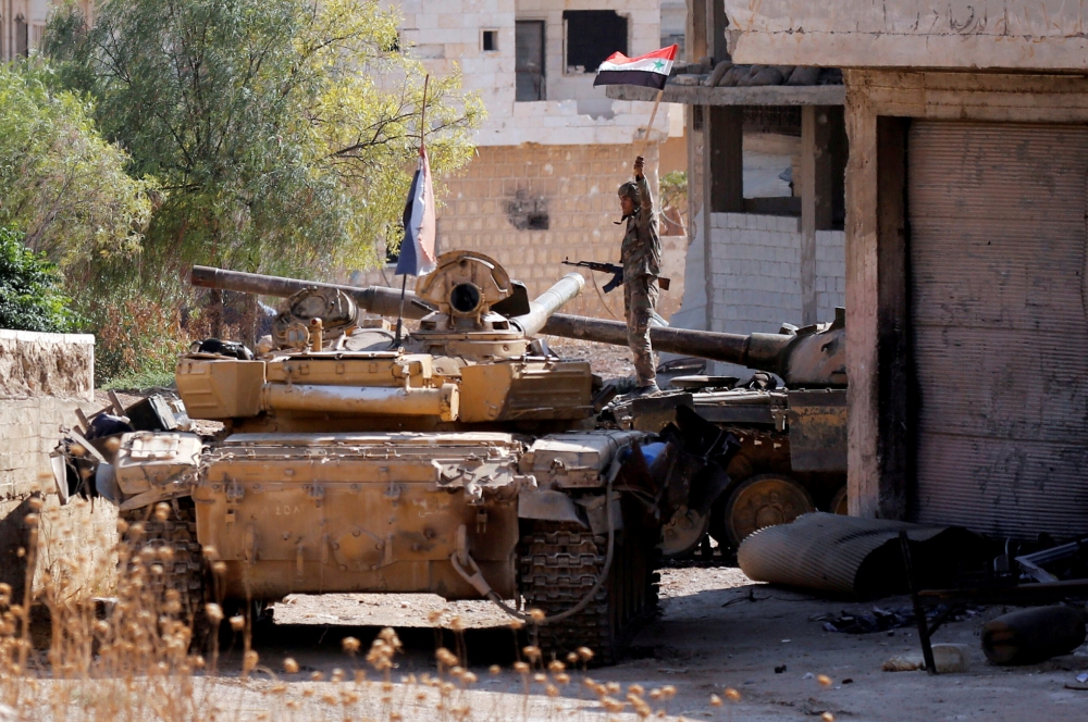 A Syrian army soldier holds a Syrian flag as he stands on a military vehicle in Khan Sheikhoun, Idlib, Syria, in this Aug. 24, 2019 file photo. — Reuters