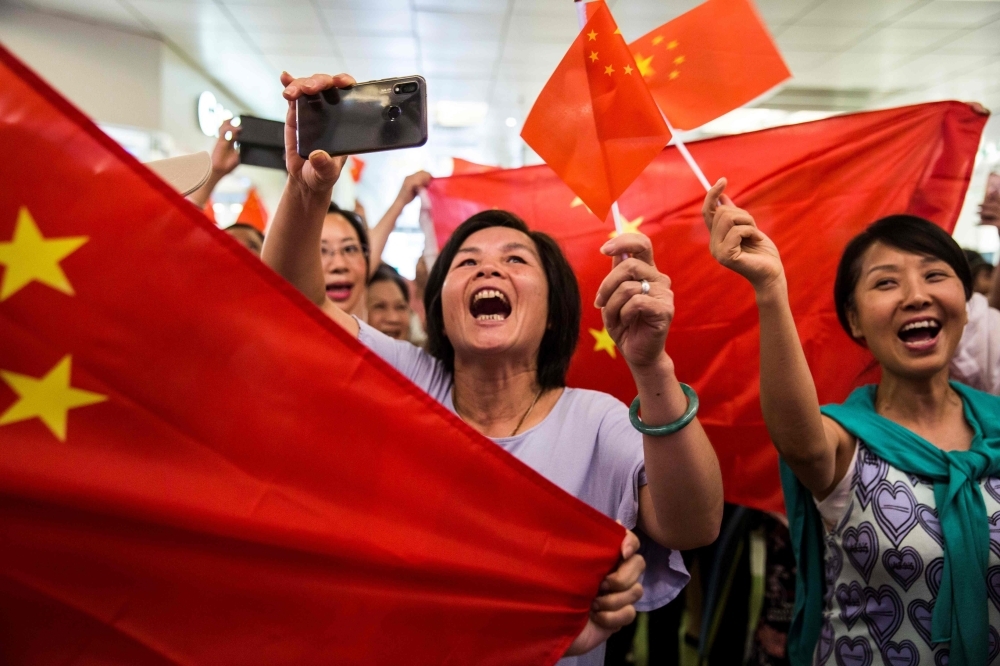 Pro-China supporters sing the national anthem inside a shopping mall in the Kowloon Bay district of Hong Kong on Saturday. -AFP 