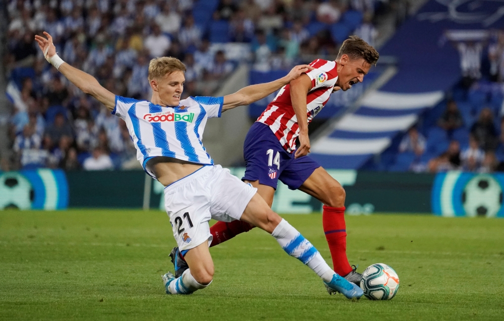 Real Sociedad's Martin Odegaard in action with Atletico Madrid's Marcos Llorente at Reale Arena, San Sebastian, Spain, on Saturday. — Reuters