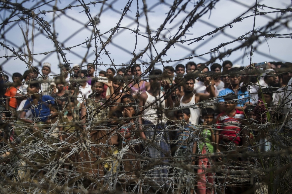 In this file photo taken on April 25, 2018, taken from Maungdaw district, Myanmar's Rakhine state on April 25, 2018 shows Rohingya refugees gathering behind a barbed-wire fence in a temporary settlement setup in a 