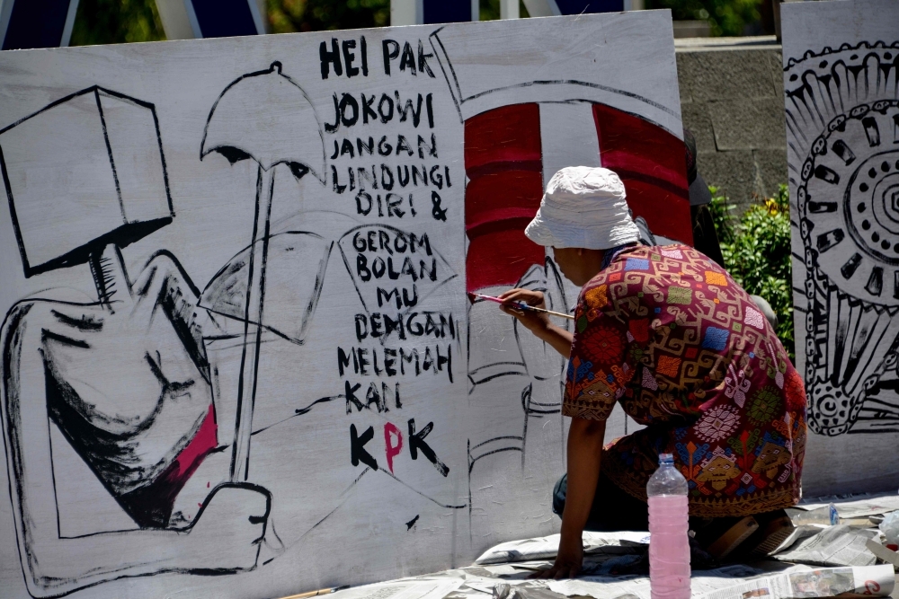 An Indonesian artist paints a protest board during a demonstration against the Corruption Eradication Commission's (KPK) law revision in Banda Aceh on Tuesday. -Reuters