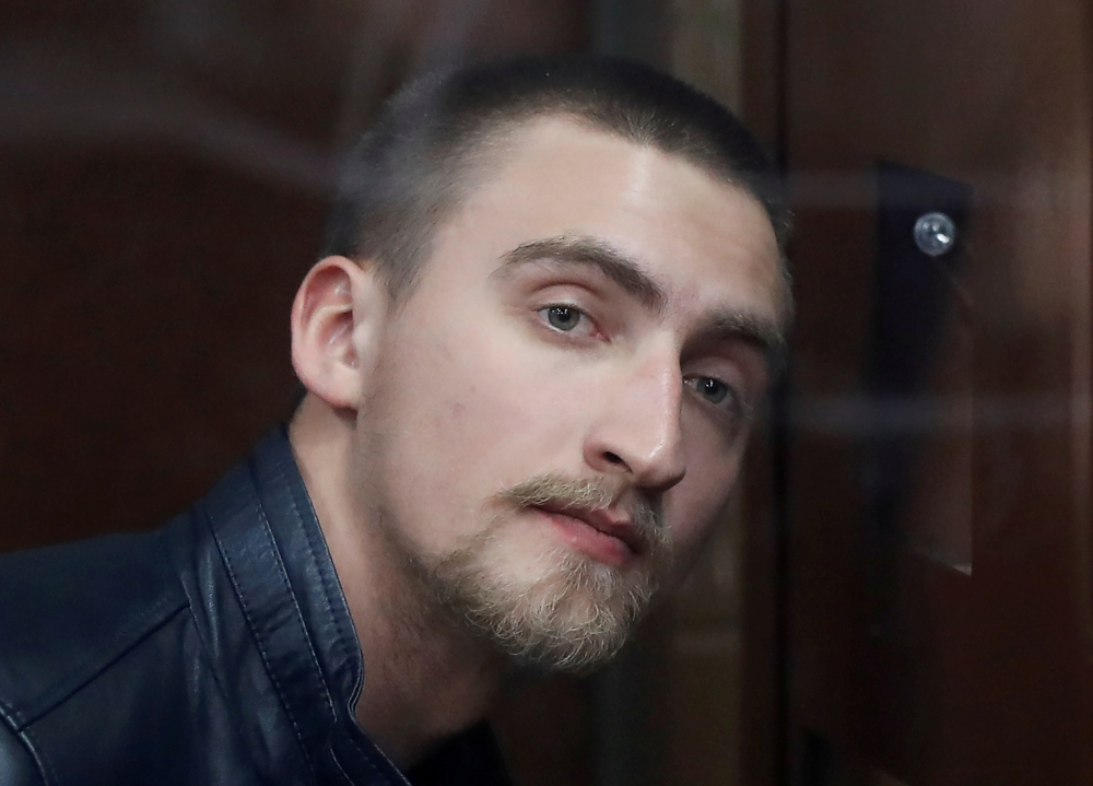 Defendant Pavel Ustinov, accused of using violence against a police officer during an unauthorized rally to demand free elections, attends a court hearing in Moscow, Russia, on Monday. — Reuters