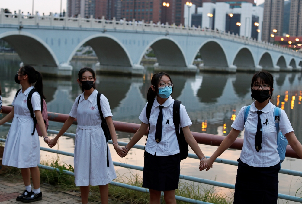 Anti-government protesters hold hands to prepare a human chain in Sha Tin at the banks of the Shing Mun River in Hong Kong, China Thursday. — Reuters