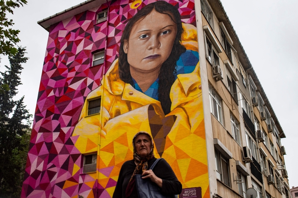 A woman walks past a building with a mural bearing a portrait of Swedish climate activist Greta Thunberg, painted by Portuguese artists Mr. Dheo and Pariz One, in the Kadikoy district in Istanbul on Friday. Swedish teen activist Greta Thunberg, who inspired the Friday's climate protests around the world, in an interview with AFP has expressed hope that climate strikes will be a 'social tipping point'.  — AFP