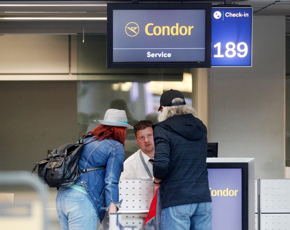 Flight passengers stand at a service desk of Condor, the German airline subsidiary of British travel giant Thomas Cook, on Monday at the airport in Duesseldorf, western Germany. Condor said it was requesting financial aid from Berlin to help keep it in the air even after its parent company declared bankruptcy. — AFP