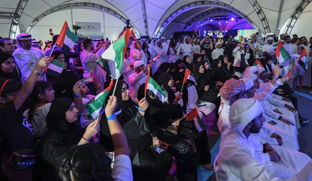 People gesture and wave Emirati national flags as they watch screens showing a Soyuz MS-15 spacecraft lifting off from Baikonur Cosmodrome in Kazakhstan as it carries carrying 35-year-old Emirati astronaut Hazzaa al-Mansoori to spend eight days aboard the International Space Station (ISS), at Mohammed Bin Rashid Space Centre (MBRSC) in Dubai on Wednesday. — AFP