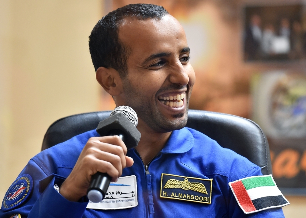 People gesture and wave Emirati national flags as they watch screens showing a Soyuz MS-15 spacecraft lifting off from Baikonur Cosmodrome in Kazakhstan as it carries carrying 35-year-old Emirati astronaut Hazzaa al-Mansoori to spend eight days aboard the International Space Station (ISS), at Mohammed Bin Rashid Space Centre (MBRSC) in Dubai on Wednesday. — AFP