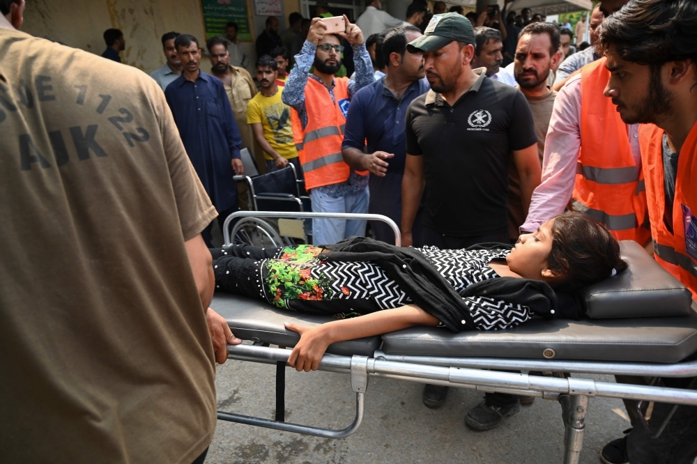 Pakistani volunteers shift a young injured following a quake of 4.7 magnitude, in Mirpur in Pakistan-controlled Kashmir, on Thursday. — AFP