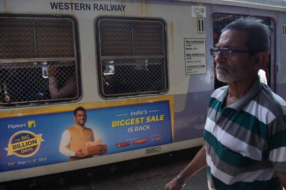 In this photograph taken on Sept. 26, 2019, a commuter walks past a train with advertisements of the upcoming festive sale of an online e-commerce portal featuring Indian cricketer Mahendra Singh Dhoni in Mumbai. E-commerce giants Amazon and Walmart-backed Flipkart kicked off a crucial battle for shoppers on Sunday ahead of India's massive festive season as retailers search for a much-needed boost to sales in a slowing economy. — AFP