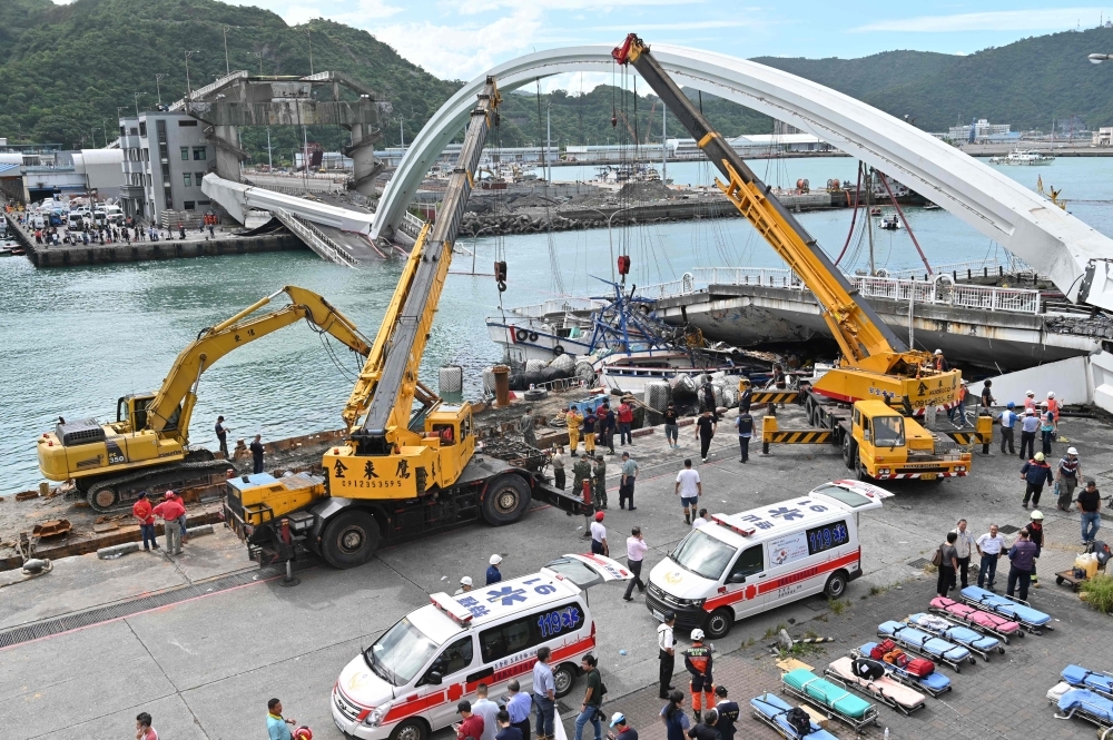 Rescue teams work at the site of a collapsed bridge in Nanfangao harbor in Suao township, Taiwan, on Tuesday. — AFP