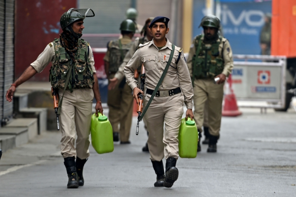 Security personnel walk as they carry water cans while strict restrictions are imposed during a lockdown in Srinagar in this Sept. 28, 2019 file photo. — AFP