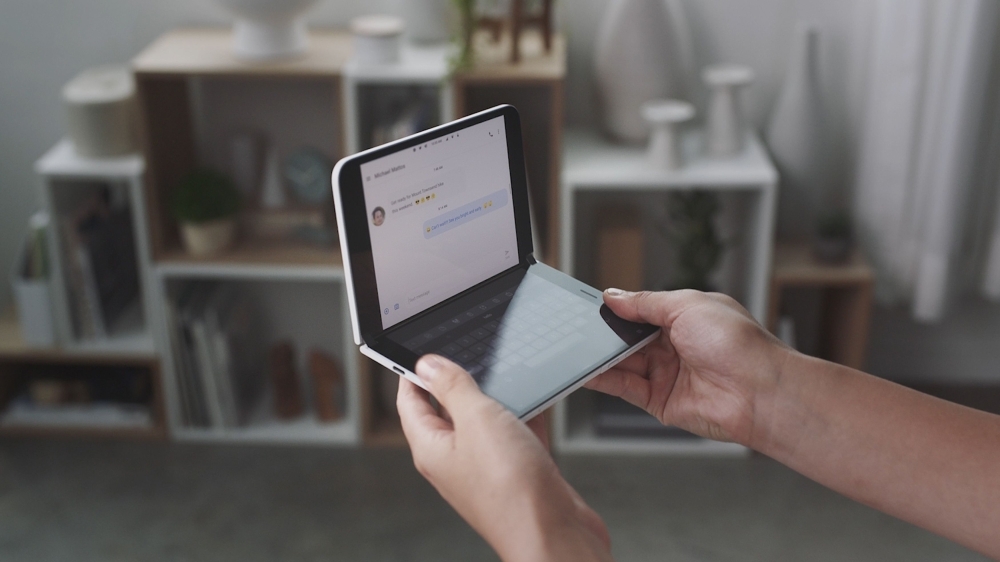 This handout photo obtained Wednesday courtesy of Microsoft shows a woman looking at a new dual-screen device Surface Duo. Microsoft unveiled Surface tablet computers with twin-screens that opened like books, and a notepad-sized version that put it back in the smartphone game. — AFP