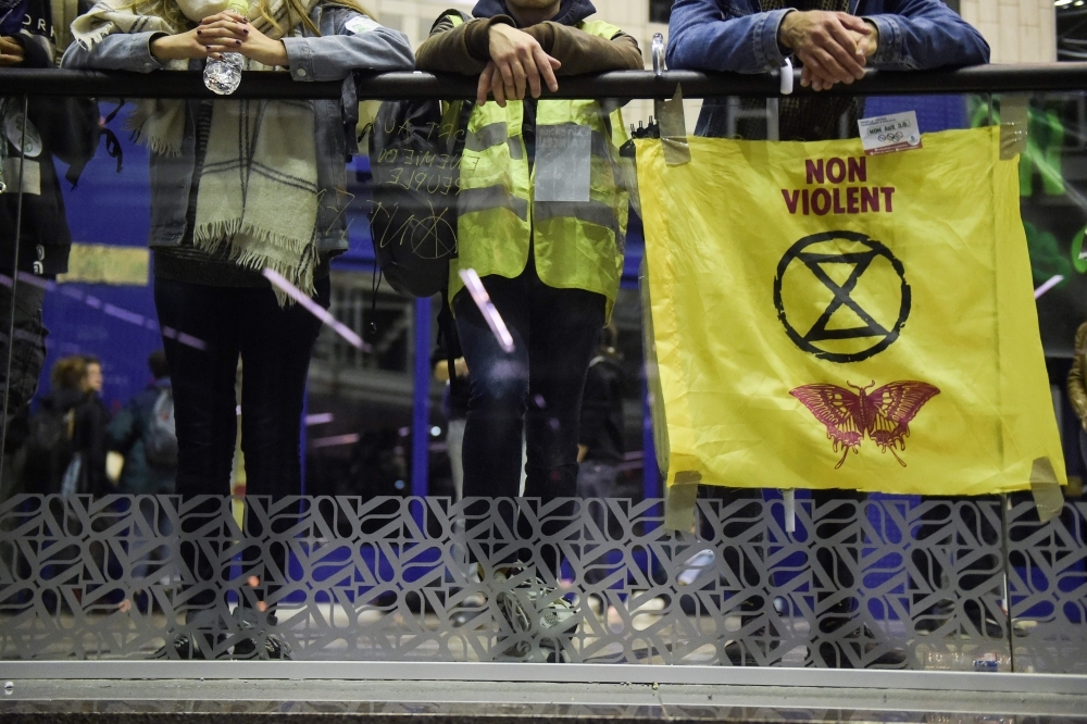 Protestors stand inside the Italie Deux shopping mall in Paris during a demonstration called by the Extinction Rebellion environmental activist movement, on Saturday. -AFP 