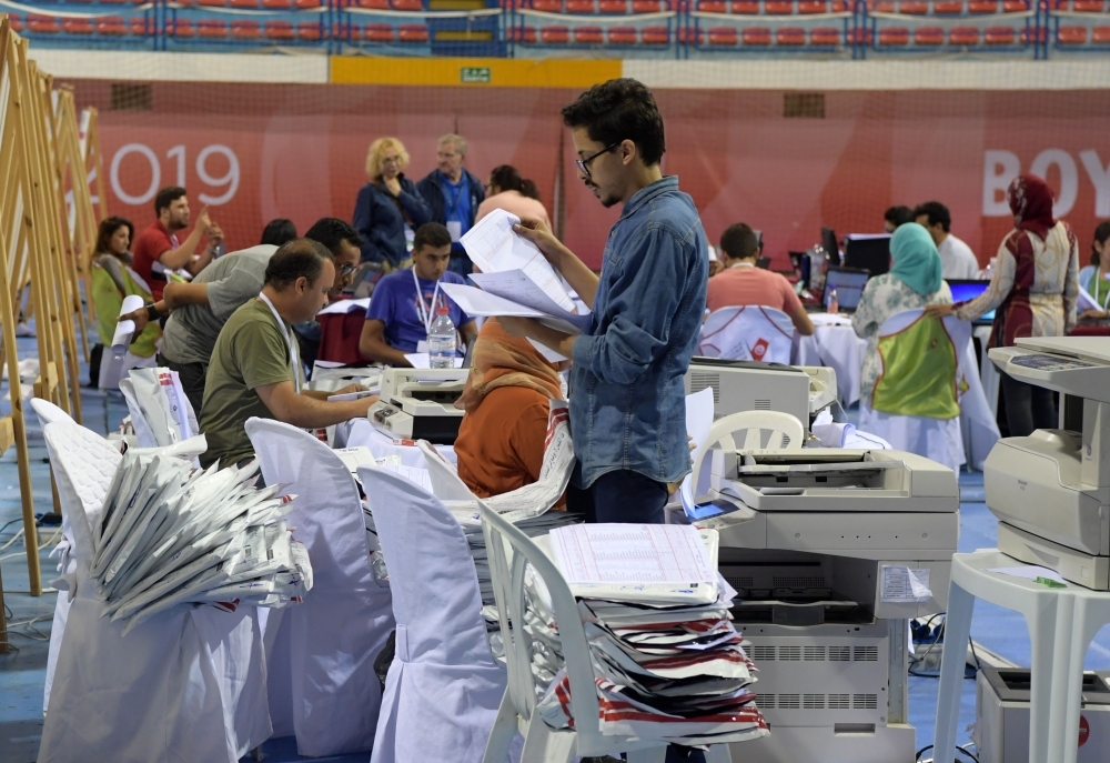 Staff members of Tunisia's Independent Higher Authority for Elections (ISIE) sort through ballot boxes of the legislative vote at a sorting station in the capital Tunis on Monday. — AFP