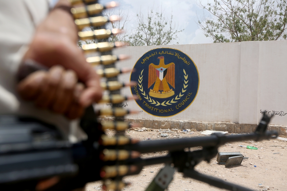 A Yemeni government soldier holds a weapon as he stands by an emblem of the STC at the headquarters of the Southern Transitional Council in Ataq, Yemen August 27, 2019. — Reuters  