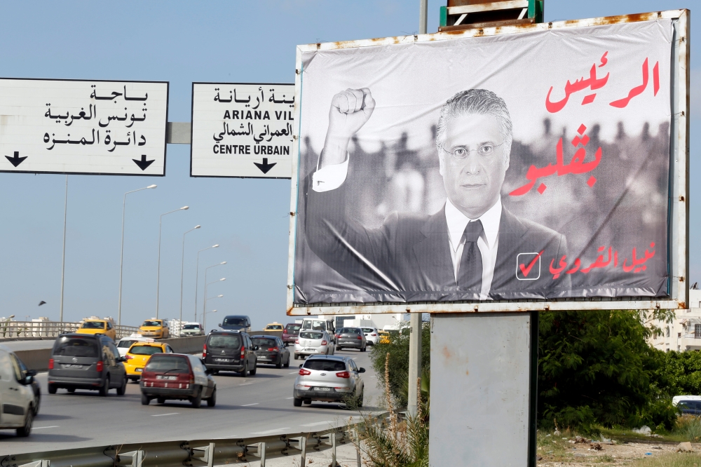 Cars drive past an election campaign billboard for Nabil Karoui, a Tunisian media mogul and presidential candidate in detention, ahead of Sunday's second round of the presidential election in Tunis, Tunisia, on Wednesday. — Reuters