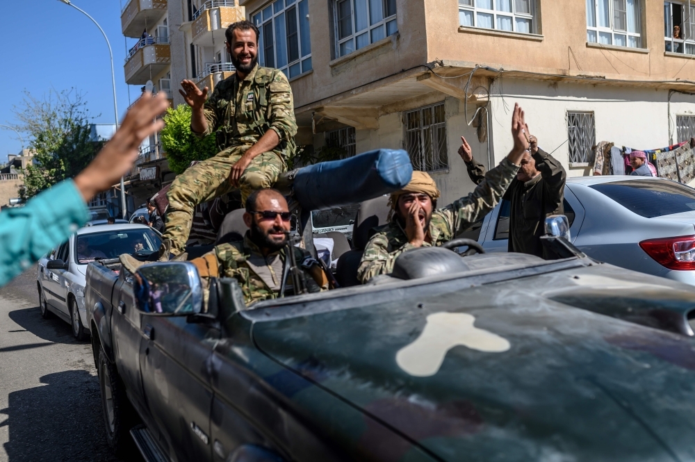 Turkey-backed Syrian opposition fighters are seen heading to Tel Abyad from Turkish gate toward Syria in Akcakale in Sanliurfa province on Thursday. — AFP 