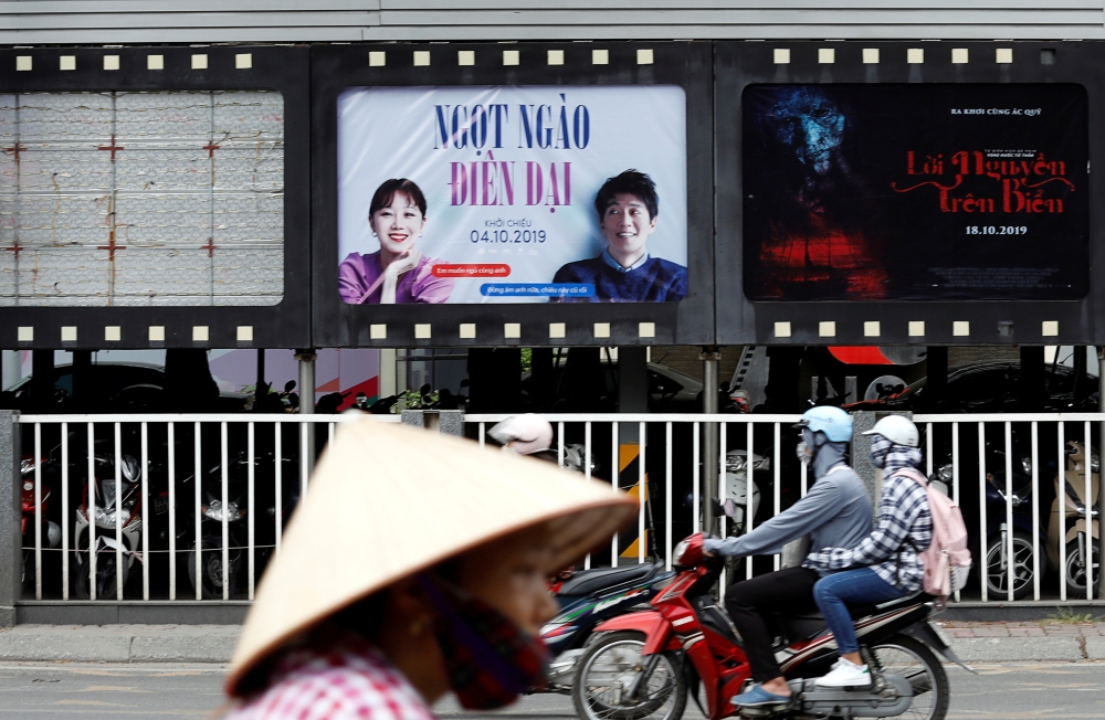 Bikers go past an empty space where a promotional poster for the DreamWorks film 