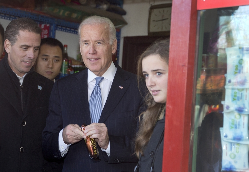 Former US Vice President Joe Biden, center, buys an ice cream at a shop as he tours a Hutong alley with his granddaughter Finnegan Biden, right, and son Hunter Biden, left, in Beijing, China, in this Dec. 5, 2013 file photo. — AFP