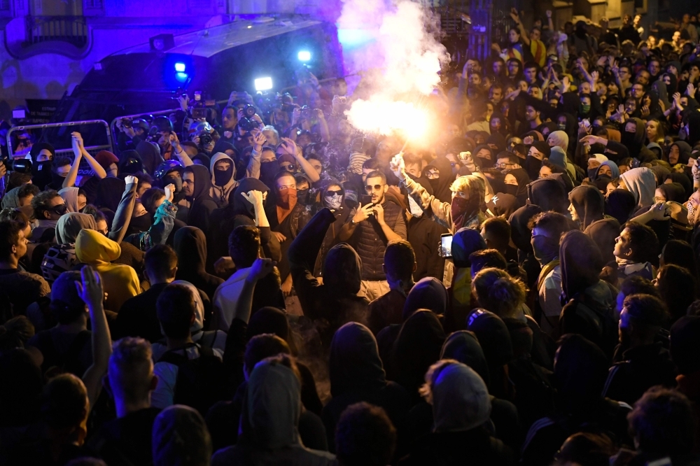 A man lights a flare during a protest in front of the Spanish Government delegations in Barcelona, Spain, on Tuesday. — AFP