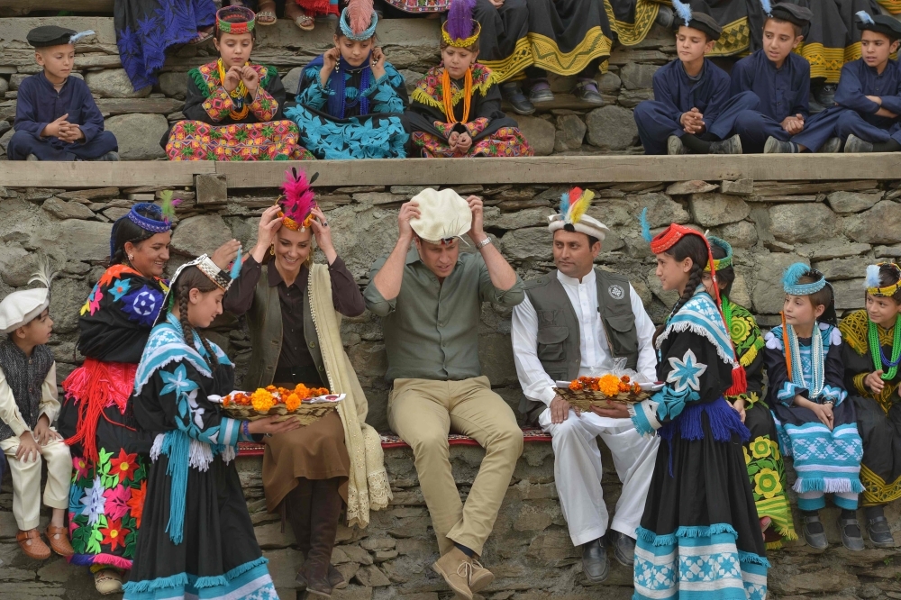 Kalash girls presents traditional hats to Britain's Prince William, center, Duke of Cambridge and his wife Britain's Catherine, fourth left, Duchess of Cambridge during their visit to the Bumburate Valley in Pakistan northern Chitral District on Wednesday. — AFP