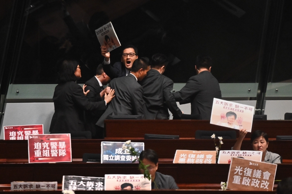 Members of security try to block pro-democracy lawmaker Lam Cheuk-ting, center-facing, as he chants slogans in protest as Hong Kong Chief Executive Carrie Lam, not pictured, holds a question and answer session at the Legislative Council (Legco) in Hong Kong on Thursday. — AFP