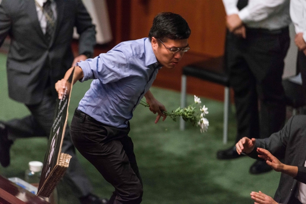 Pro-democracy lawmaker Au Nok-hin (C) stands on the table inside the chamber in protest as Hong Kong Chief Executive Carrie Lam (not pictured) holds a question and answer session at the Legislative Council (Legco) in Hong Kong on Thursday. Pro-democracy lawmakers were dragged out of Hong Kong's legislature by security guards after they heckled the city's pro-Beijing leader for a second day running, the latest outburst of political rancor in the strife-torn city.  — AFP