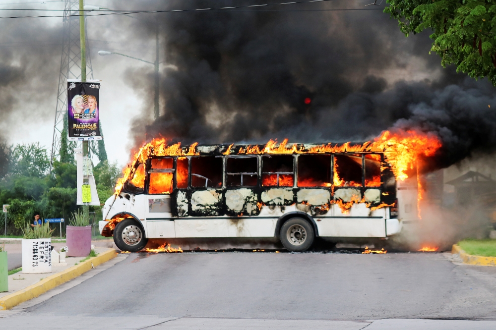 A burning bus, set alight by cartel gunmen to block a road, is pictured during clashes with federal forces following the detention of Ovidio Guzman, son of drug kingpin Joaquin 