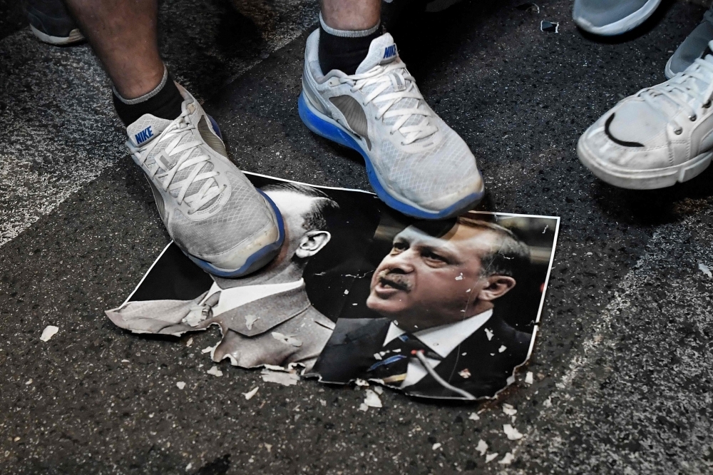 Protesters step on a paper depicting a combination of pictures of Turkish President Recep Tayyip Erdogan, right, and leader of the Nazi Party, Adolf Hitler, left, during a demonstration outside the US embassy in Athens on Thursday to protest against Turkish offensive against Syria's Kurdish forces and the stance of its NATO allies. — AFP