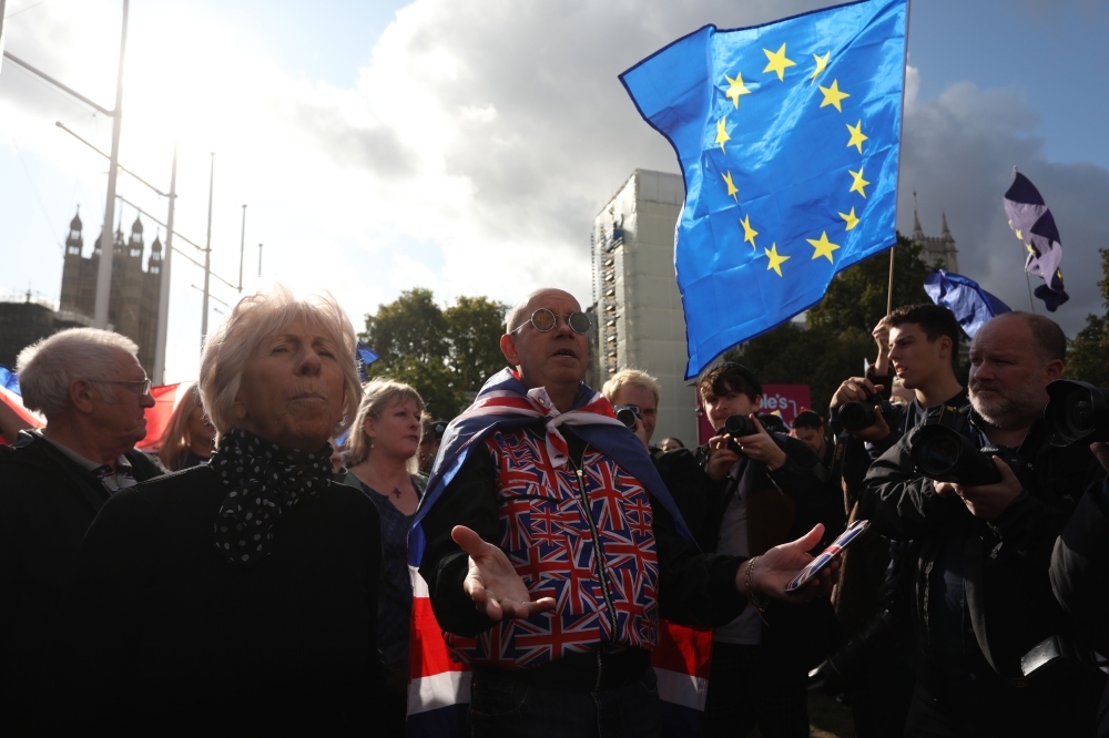 Pro-Brexit demonstrators (center) speak with anti-Brexit demonstrators in Parliament Square in central London on Saturday, ahead of a rally by activists from the People's Vote organization who are calling for a second referendum on Brexit. — AFP 