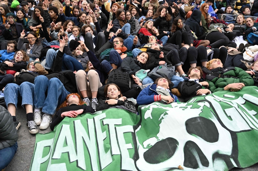 High school students lie on the ground as they protest climate change in front of the Canadian prime minister's campaign office in Montreal on October 18, 2019.  Youth in Montreal and around the world have protested for the environment on Fridays for several months, following the example of Swedish activist Greta Thunberg, who began to protest in August 2018. Youth in Montreal on October 18 called on politicians to take bolder action to stop climate change, ahead of Canada's federal election on October 21. / AFP / Louis BAUDOIN
