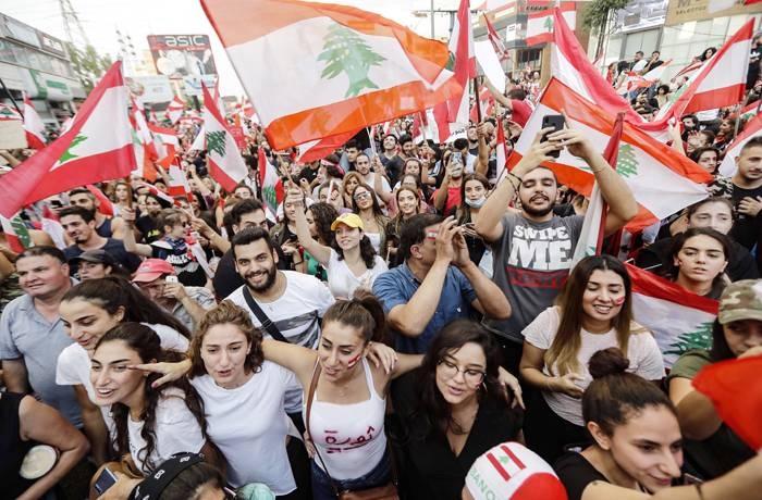 Lebanese demonstrators wave national flags on a highway linking Beirut to north Lebanon, in Zouk Mikael on October 19, 2019, a day after demonstrations swept through the eastern Mediterranean country in protest against dire economic conditions.  Thousands of protesters outraged by corruption and proposed tax hikes burned tyres and blocked major highways in Lebanon on Friday, prompting the premier to give his government partners three days to support a reform drive. / AFP / JOSEPH EID
