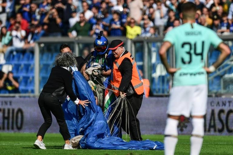 Security staff evacuate a parachutist who landed on the pitch at Sassuolo's stadium in Reggio-Emilia during a game against Inter Milan. — AFP