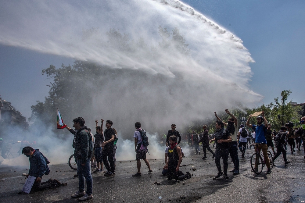 Demonstrators clash with riot police during protests in Santiago on Sunday. — AFP